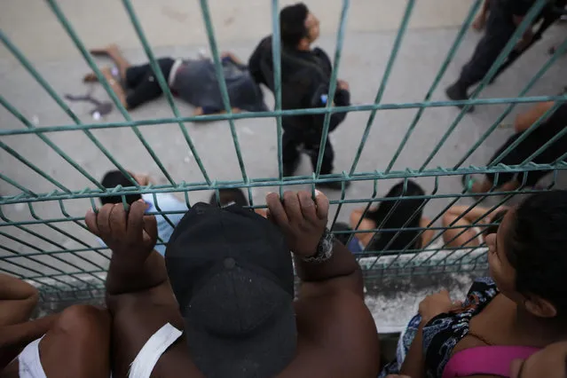 People look at the body of a alleged drug trafficker killed during a shooting between police at Pavuna slum, in Rio de Janeiro, Brazil, Thursday, March 30, 2017. (Photo by Diego Herculano/AP Photo)