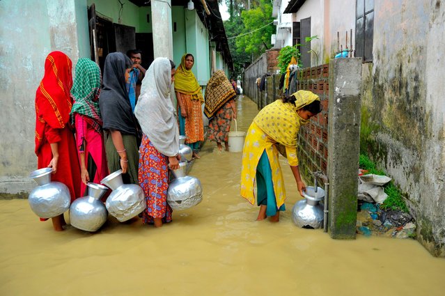 Family members collect clean water from supply pipes in Machimpur, Bangladesh on June 2, 2024, where people have been stranded after heavy flooding. Although the water has receded slowly in the last three days, there is still flood water in the low-lying areas of the city.(Photo by Md Rafayat Haque Khan/ZUMA Press Wir/Rex Features/Shutterstock)