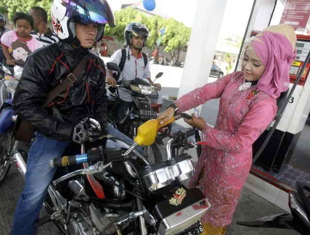 A fuel-station woman employee with an Indonesian traditional dress known as “kebaya“, fills petrol into a vehicle during the Kartini Day celebrations in Banda Aceh, Indonesia April 21, 2014. Kartini, a prominent Javanese and an Indonesian national heroine, regarded as a hero of education in Indonesia, is known for being a pioneer of the revival of indigenous women. (Photo by Hotli Simanjuntak/EPA)