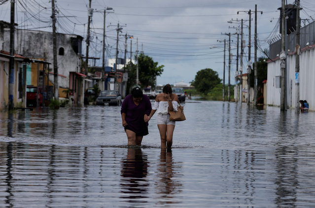 People walk on a flooded street after heavy rainfall in Duran, Ecuador April 4, 2017. (Photo by Henry Romero/Reuters)