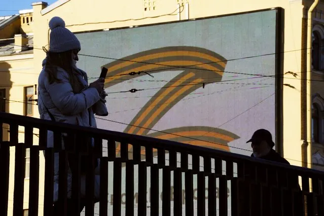 People walk past the letter Z, which has become a symbol of the Russian military, on an advertisement screen in St. Petersburg, Russia, Thursday, March 10, 2022. (Photo by AP Photo/Stringer)