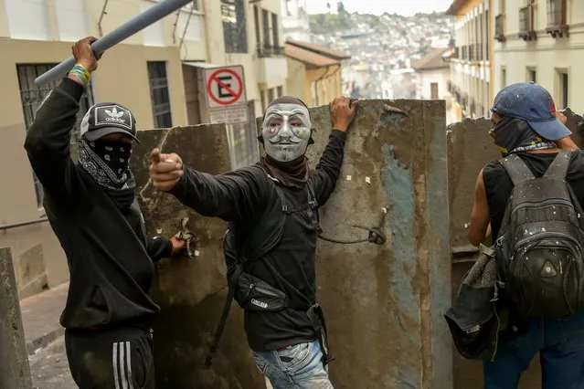 Demonstrators protect themselves with makeshift shields during clashes with riot police in Quito, as thousands march against Ecuadorean President Lenin Moreno's decision to slash fuel subsidies, on October 9, 2019. (Photo by Rodrigo Buendia/AFP Photo)