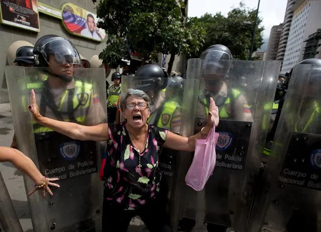 A demonstrator is blocked by Bolivarian National police during an anti-government march to the headquarters of the national electoral body, CNE, in Caracas, Venezuela, Wednesday, May 18, 2016. Opposition protesters were blocked from reaching the CNE as they demand the government allow it to pursue a recall referendum against Venezuela's President Nicolas Maduro. (Photo by Fernando Llano/AP Photo)