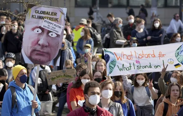 People hold protest poster as they take part in a “Fridays For Future” climate protest rally in Berlin, Germany, Friday, March 25, 2022. German slogan reads “Global Climate Strike, Stop Putin, Stop Oil And Gas Immediately”. (Photo by Michael Sohn/AP Photo)