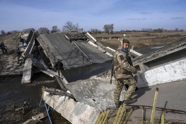 A soldier stands on a bridge destroyed by the Ukrainian army to prevent the passage of Russian tanks near Brovary, in the outskirts of Kyiv, Ukraine, Monday, March 28, 2022. (Photo by Rodrigo Abd/AP Photo)