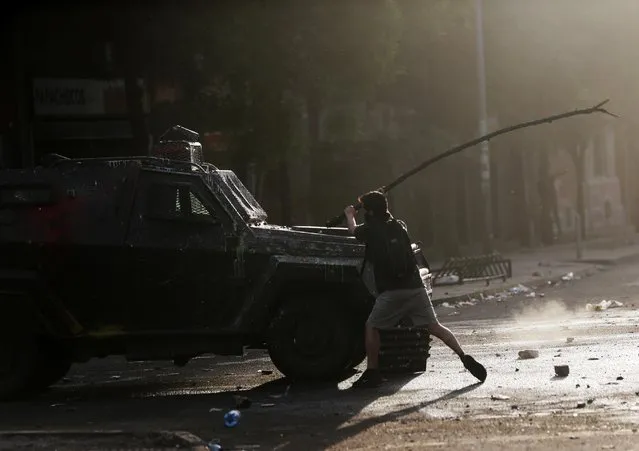 A demonstrator attacks a vehicle belonging to the security forces during a protest against Chile's state economic model in Santiago, Chile October 22, 2019. (Photo by Ivan Alvarado/Reuters)