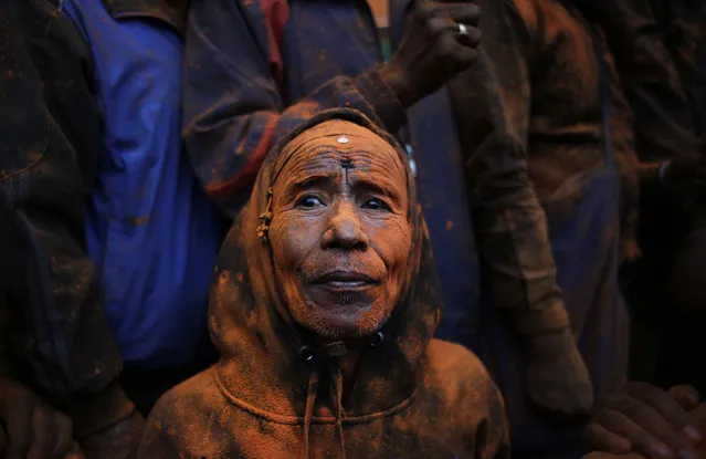In this Saturday, April 15, 2017 photo, a Nepalese, face smeared with vermilion powder, watches a chariot being carried during Sindoor Jatra festival in Bhaktapur, Nepal. Devotees mark the festival by playing traditional drums, singing, dancing and carrying chariot of various deities around town while throwing vermilion powder to welcome the advent of spring and the New Year. (Photo by Niranjan Shrestha/AP Photo)