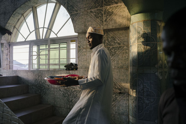 A volunteer distributes food for Iftar on the fourth day of the Holy month of Ramadan in Freetown on March 26, 2023. The food, bought from donations, will be distributed later to nearly 500 people at the Jamiatul Haque Mosque to break the fast after the call to the Maghrib prayer. (Photo by Carmen Abd Ali/AFP Photo)