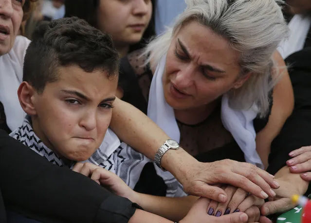 Omar, left, and his mother Lara, the son and the wife of of Alaa Abu Fakher, who was killed by a Lebanese soldier in Tuesday night protests south of Beirut, attend his funeral, in Choueifat neighborhood, Lebanon, Thursday, November 14, 2019. For nearly a month, the popular protests engulfing Lebanon have been startlingly peaceful. But the shooting death of Fakher, a 38-year-old father by a soldier, the first such fatality in the unrest, points to the dangerous, dark turn the country could be heading into. (Photo by Hussein Malla/AP Photo)