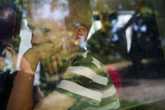 A boy sits in a bus during evacuations in Pokrovsk, Donetsk region, Ukraine, Monday, August 19, 2024. Due to the advance of Russian troops, the war affects more and more new settlements to the west of the Donetsk region and intensive shelling forced people to leave their homes. (Photo by Evgeniy Maloletka/AP Photo)