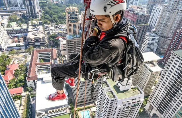 A worker scales a skyscraper to install Christmas and New Year lights in Bangkok, Thailand on December 10, 2019. (Photo by Mladen Antonov/AFP Photo)