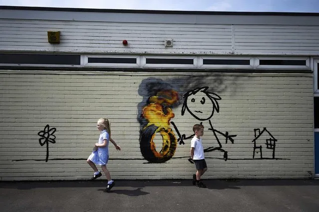 Reception class school children skip past a mural, attributed to graffiti artist Banksy, painted on the outside of a class room at the Bridge Farm Primary School in Bristol, Britain June 6, 2016. (Photo by Dylan Martinez/Reuters)