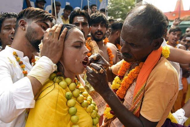 A devotee gets her cheeks pierced with a metal rod by a priest while taking part in a procession to honour the Hindu goddess Mariamman in Amritsar on May 8, 2022. (Photo by Narinder Nanu/AFP Photo)