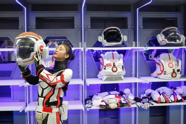 A staff member demonstrates how she puts on the helmet of a mock space suit at the C-Space Project Mars simulation base in the Gobi Desert outside Jinchang, Gansu Province, China, April 17, 2019. The facility – comprising several interconnected modules including a greenhouse and a mock decompression chamber – opened its doors to the public. (Photo by Thomas Peter/Reuters)