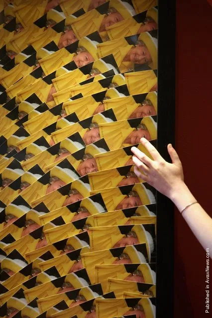 Charlotte Roirdan, from Lyon and Turnbull, poses near portrait of a woman wearing a bikini made entirely out of postcards of the Queen