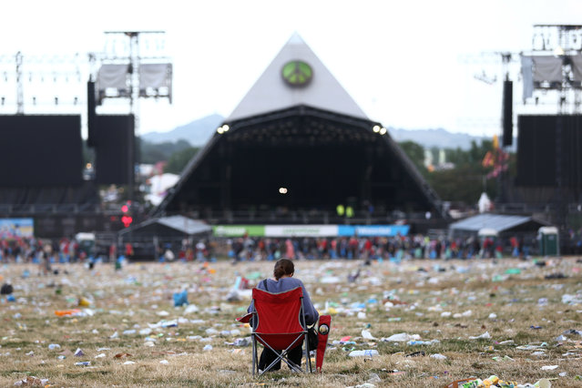 A person sits in a rubbish-filled field near the Pyramid Stage area at the Glastonbury Festival in Pilton, Britain on June 26, 2023. The Glastonbury Festival is a five-day festival of music, dance, theatre, comedy and performing arts running from 21 to 25 June 2023. (Photo by Adam Vaughan/EPA/EFE)