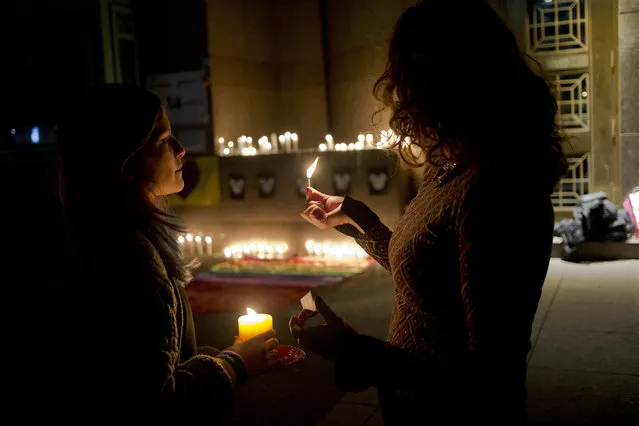 Two woman light candle during a vigil in front of the U.S. embassy to remember the victims of the mass shooting at the Pulse Orlando, Fla. nightclub, in Santiago, Chile, Sunday, June 12, 2016. A gunman opened fire inside the nightclub early Sunday, killing at least 50 people before dying in a gunfight with SWAT officers, police said. (Photo by Esteban Felix/AP Photo)
