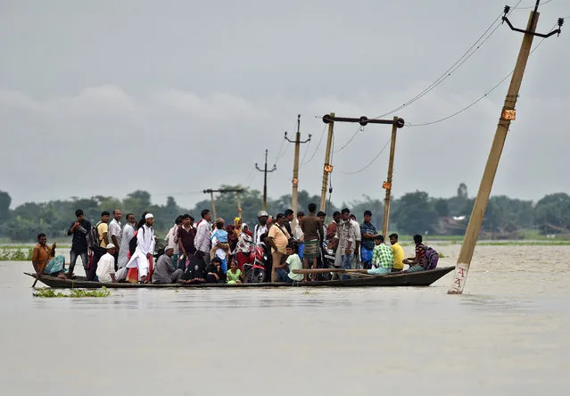 Villagers use a boat to cross a flooded road at Asigarh village in Morigaon district in the northeastern state of Assam, India, July 4, 2017. (Photo by Anuwar Hazarika/Reuters)