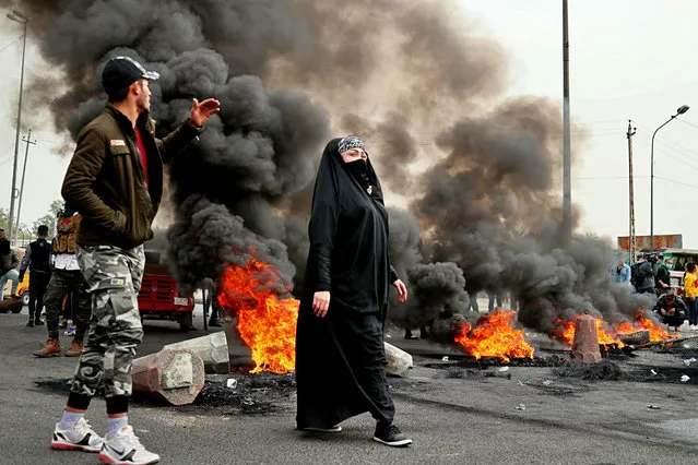 Anti-government protesters set fires and close streets during ongoing protests in downtown Baghdad, Iraq, Sunday, January 19, 2020. Black smoke filled the air as protesters burned tires to block main roads in the Iraqi capital Baghdad, expressing their anger at poor services and shortages despite religious and political leaders calling for calm. (Photo by Hadi Mizban/AP Photo)