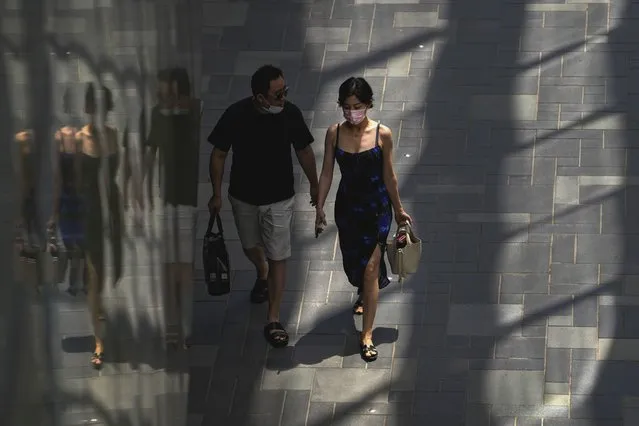 A couple wearing face masks walk through a shopping mall in Beijing, Monday, June 6, 2022. (Photo by Andy Wong/AP Photo)