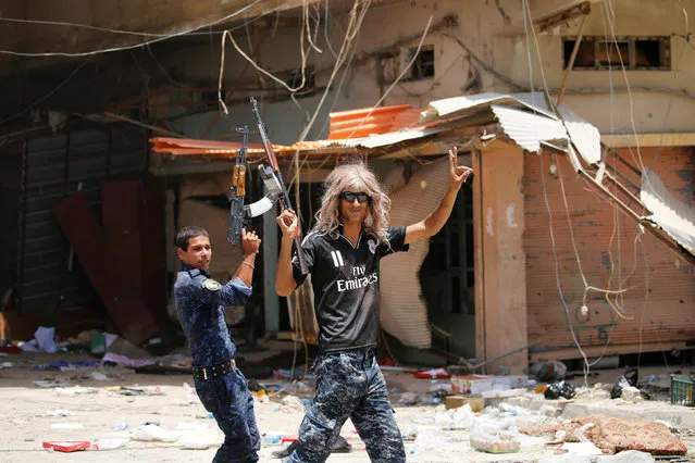 A member of Iraqi government forces celebrate along a street in Falluja after government forces recaptured the city from Islamic State militants, Iraq, June 27, 2016. (Photo by Thaier Al-Sudani/Reuters)