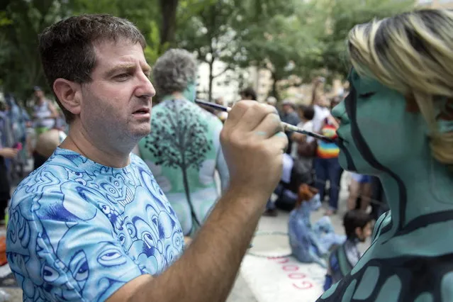 Artist Andy Golub paints a model at Columbus Circle as body-painting artists gathered to decorate nude models as part of an event lead by Golub, Saturday, July 26, 2014, in New York. Golub says New York was the only city in the country that would allow his inaugural Bodypainting Day. (Photo by John Minchillo/AP Photo)