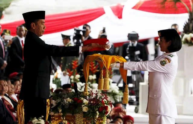 Indonesian President Joko Widodo (L) passes a national flag to a student during celebrations for Indonesia's 70th Independence Day at the Presidential Palace in Jakarta, August 17, 2015. (Photo by Reuters/Beawiharta)