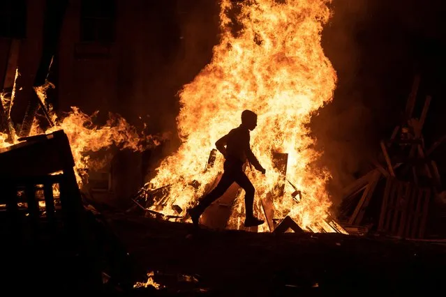 An Ultra-Orthodox Jewish boy runs next to a bonfire during celebrations for the Jewish holiday of Lag B'Omer in Bnei Brak near Tel Aviv on May 18, 2022. (Photo by Nir Elias/Reuters)
