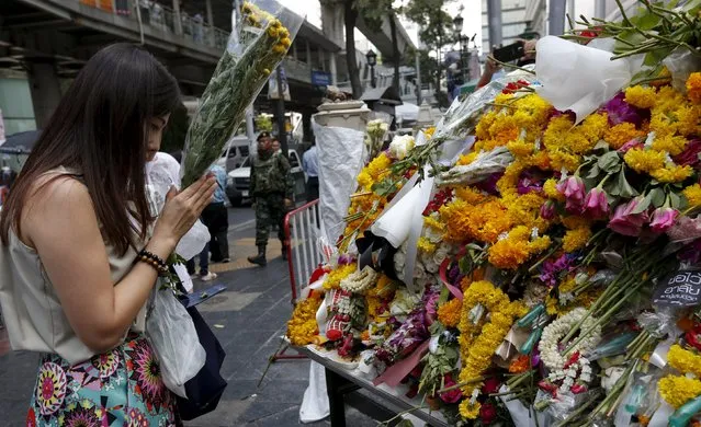 A woman places a bouquet of flowers at the Erawan shrine, the site of Monday's deadly blast, in central Bangkok, Thailand, August 20, 2015. (Photo by Chaiwat Subprasom/Reuters)