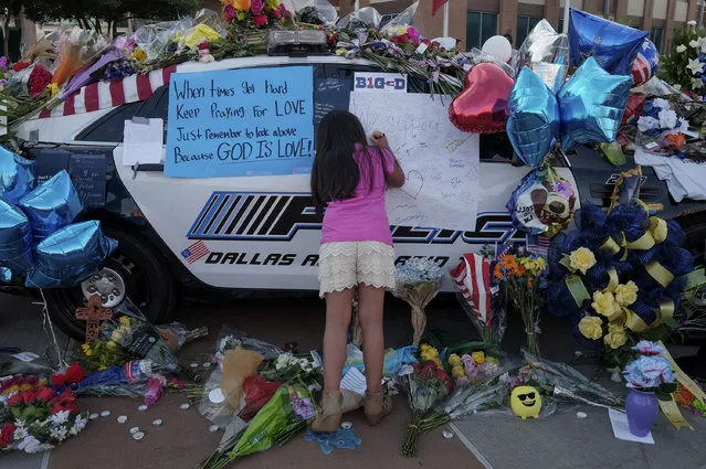 Jasmine Ruiz, 9, of San Antonio writes a note on one of two one of two police cars in front of police headquarters in Dallas, TX, on July 9, 2016. The notes were written by community members and visitors in support of police and in memory of the police officers who were killed by a sniper on July 7. Ruiz and her family came from San Antonio specifically to honor the fallen. (Photo by Bonnie Jo Mount/The Washington Post)