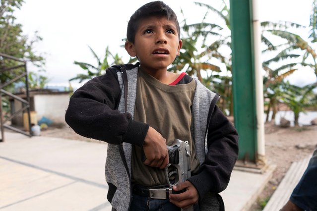 Miguel Toribio, 11, puts a pistol belonging to his father into his belt, before demonstrating newly learnt skills from military-style weapons training, to a Reuters journalist in Ayahualtempa, Mexico, February 3, 2020. (Photo by Alexandre Meneghini/Reuters)