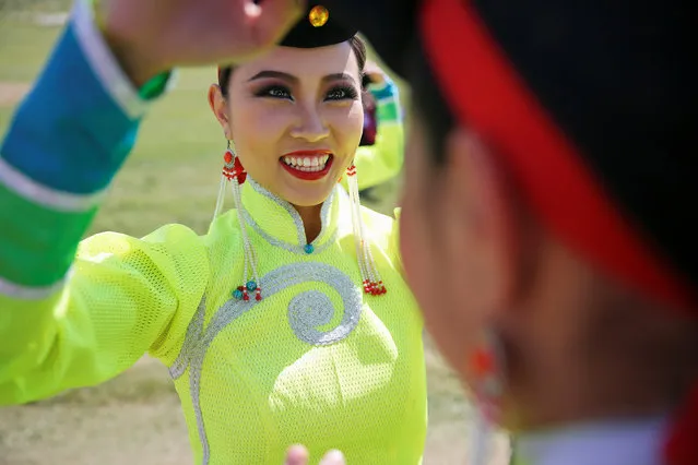 Performers help each other with costumes as they wait delegations to arrive for traditional nomadic Naadam festival performance during the Asia-Europe Meeting (ASEM) summit just outside Ulaanbaatar, Mongolia, July 15, 2016. (Photo by Damir Sagolj/Reuters)