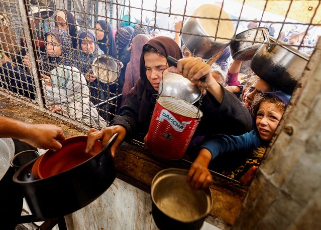 Palestinians gather to receive food cooked by a charity kitchen, amid a hunger crisis, as the Israel-Hamas conflict continues, in Khan Younis, southern Gaza Strip, on November 24, 2024. (Photo by Mohammed Salem/Reuters)