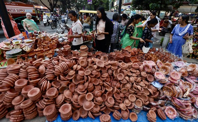 People visit shops of earthen lamps, known as Diya, flowers and decorative lights ahead of Diwali festival in Bangalore, India, 29 October 2024. Diwali, the Hindu festival of lights, symbolizes the victory of good over evil, and commemorates Lord Rama's return to his kingdom Ayodhya after completing a 14-year exile. Diwali will be celebrated this year on 31 October. (Photo by Jagadeesh N.V./EPA/EFE)