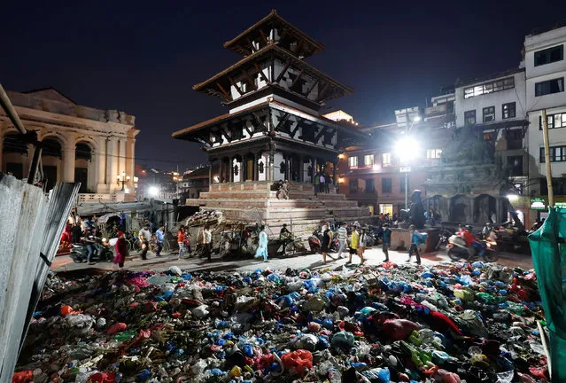 People walk near the pile of garbage dumped along the street in Bashantapur Durbar Square, a UNESCO world heritage site, as locals from a village near the dumping site protest against garbage being dumped in their area by obstructing garbage trucks from reaching the dumping site, in Kathmandu, Nepal on June 7, 2022. (Photo by Navesh Chitrakar/Reuters)