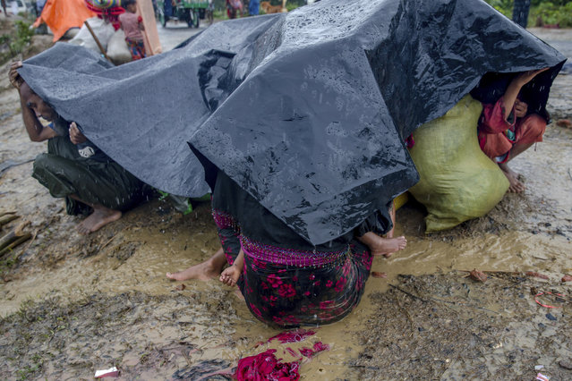 A Rohingya Muslim family, who crossed over from Myanmar into Bangladesh, take cover under a plastic sheet on a roadside during a rain storm near Balukhali refugee camp, Bangladesh, Sunday, September 17, 2017. (Photo by Dar Yasin/AP Photo)