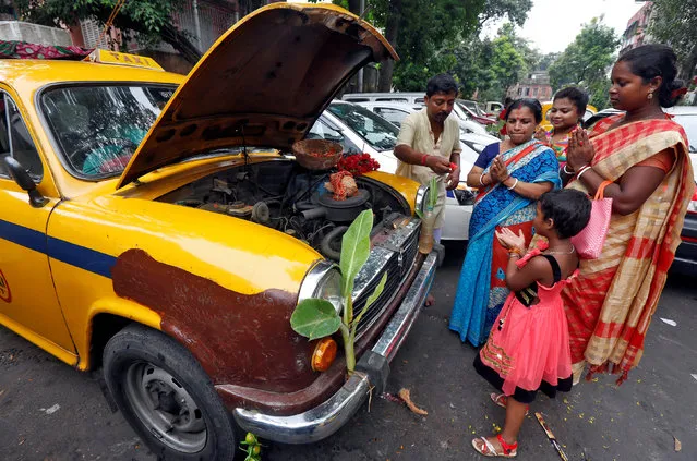 Family members of a taxi driver offer prayer in front of their taxi during the Vishwakarma Puja or the festival of the Hindu deity of architecture and machinery in Kolkata, India, September 17, 2017. (Photo by Rupak De Chowdhuri/Reuters)