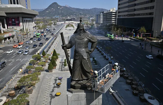 A South Korean worker sprays water to wash the bronze statue of Admiral Yi Sun-Shin, who won a major naval victory over Japan in the 16th century, during a street and park clean-up event for spring at Gwanghwamun square in Seoul on April 9, 2020. (Photo by Jung Yeon-je/AFP Photo)