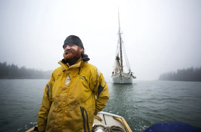 In this photo made Saturday, May 25, 2013, rain and fog doesn't dampen sailor Rob Millbrandt's mood as he shuttles passengers from the schooner Mary Day, background, for  visit to Isle Au Haut, Maine. (Photo by Robert F. Bukaty/AP Photo)