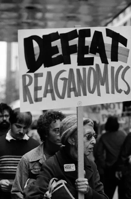 Woman demonstrator holds “Defeat Reaganomics” sign down the street from hotel in which President Reagan stayed in Chicago, September 3, 1981. Police kept the demonstrators one-half block from the President. (Photo by Jim Bourdier/AP Photo)