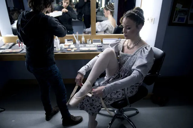 In this Friday, September 15, 2017 photo, a dancer puts her ballet shoes on before a dress rehearsal for Romeo and Juliet in Montevideo, Uruguay. About 70 professional dancers in the Uruguayan capital train under the eye of a man who wants to turn the ballet company of this small South American nation into one of the best in the world. (Photo by Matilde Campodonico/AP Photo)