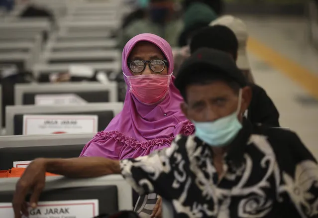 People wearing face masks sit spaced apart as a social distancing effort to help curb the spread of the coronavirus in a train station's waiting area, Tuesday, April 7, 2020, in Jakarta, Indonesia. (Photo by Dita Alangkara/AP Photo)