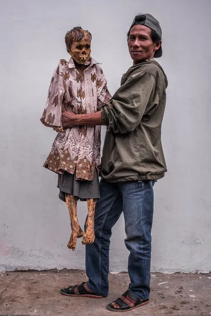 Andaris Palulun is given new clothes by his brother Ferri before returning to the family tomb. He died 20 years ago. (Photo by Claudio Sieber Photography/The Guardian)