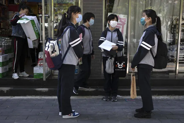 Students, wearing face masks, chat before attending school near a middle school in Beijing on Monday, May 11, 2020. The Chinese capital partially reopen schools for some students on Monday as authorities push to restore normalcy after the lockdown to fight the coronavirus. (Photo by Ng Han Guan/AP Photo)