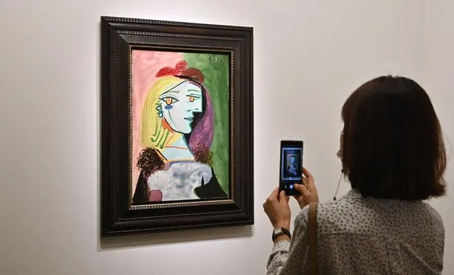 A woman uses a phone next to Pablo Picasso's “Femme au beret rouge a pompon, 1937” during the Frieze Seoul 2022 art fair in Seoul on September 2, 2022. (Photo by Jung Yeon-je/AFP Photo)