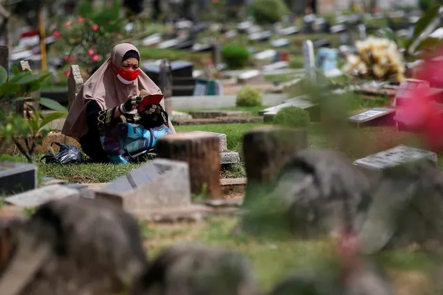 A muslim woman wearing a protective mask reads at a relative's grave as she visits a cemetery complex ahead of the holy fasting month of Ramadan, amid the spread of the coronavirus disease (COVID-19), in Jakarta, Indonesia, April 23, 2020. (Photo by Willy Kurniawan/Reuters)