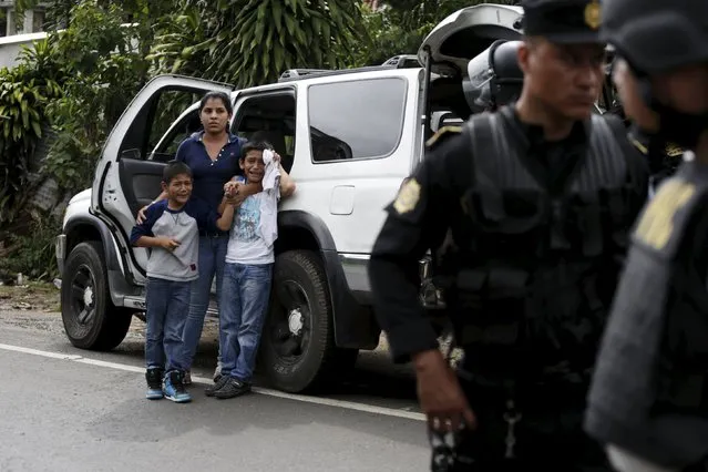 A woman hugs two crying children as police search their vehicle for demonstrators who had taken part in a protest against the re-election of the city's mayor Rubelio Recinos of the Patriot Party in Barberena, northwest of Guatemala City, September 8, 2015. (Photo by Jorge Dan Lopez/Reuters)