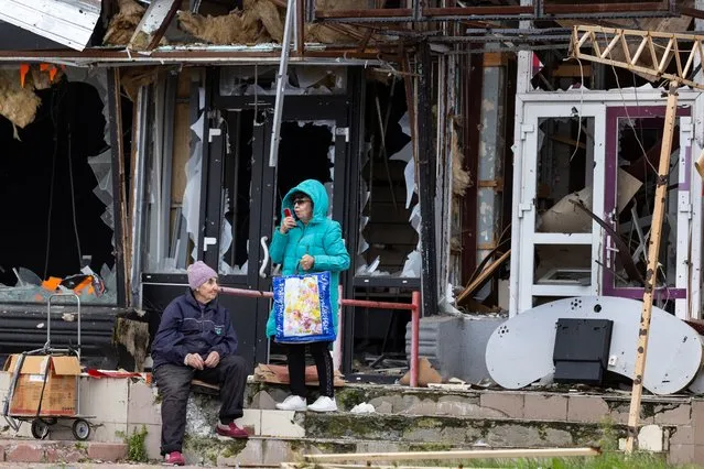 Women try to communicate on a mobile phone outside a destroyed building waiting for humanitarian aid to arrive on October 3, 2022 in Izium, Ukraine. Izium is still without electricity and water since the town was liberated. (Photo by Paula Bronstein/Getty Images)