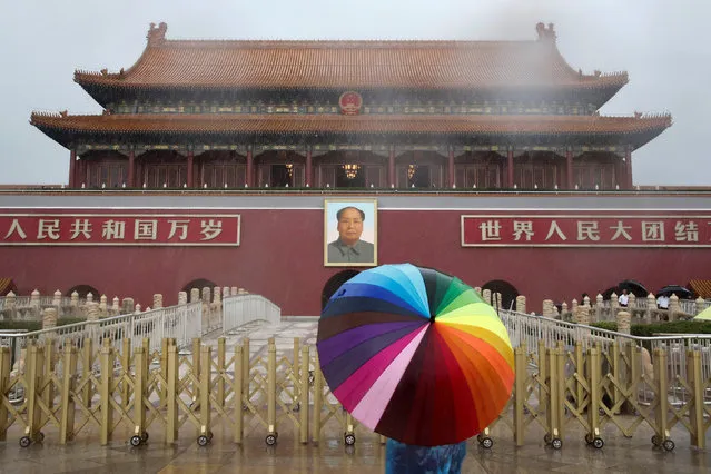 A tourist holds an umbrella as he stands in front of the Tiananmen Gate and a giant portrait of Chinese late Chairman Mao Zedong on a day of heavy rain in Beijing, China, July 20, 2016. (Photo by Thomas Peter/Reuters)