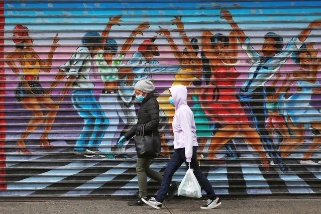 Two pedestrians wear masks while walking past a mural of people dancing as the outbreak of the coronavirus disease (COVID-19) continues in the Manhattan borough of New York U.S., May 8, 2020. (Photo by Lucas Jackson/Reuters)